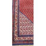 A North West Persian Woollen Carpet with an all over design upon a red, blue and cream ground within