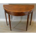 A 19th Century Mahogany And Cross Banded Demi Lune Card Table, the hinged top above a plain frieze