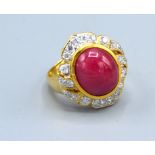 An 18ct. Gold Ruby And Diamond Ring set with a central cabochon ruby surrounded by diamonds within a