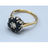 A 9ct. Gold Sapphire And Diamond Cluster Ring with a central diamond surrounded by sapphires, claw