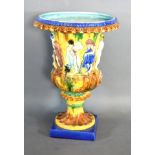 A Majolica Urn decorated with a band of figures upon a shaped stepped base 32 cms tall