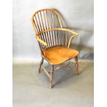 A 19th Century Elm Windsor Armchair, the spindle back above a panel seat with shaped arms, raised