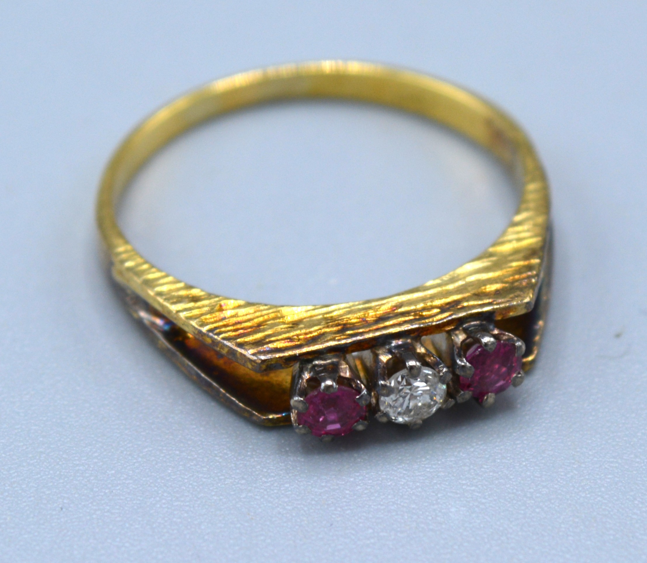 An 18ct Yellow Gold Ruby And Diamond Ring set with central diamond flanked by two rubies within a