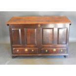 A George III Oak Mule Chest, the hinged top above a four panel front and two drawers with brass knob