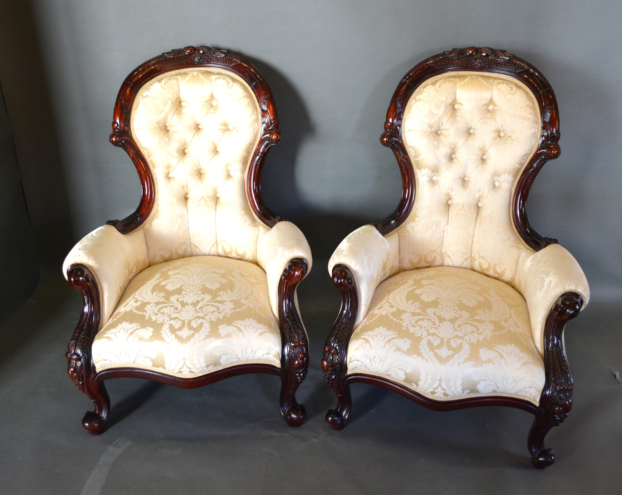 A Pair Of Victorian Style Drawing Room Armchairs, each with a carved and button upholstered back
