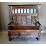 An Oak Settle, the carved and pierced back above a panel seat flanked by stiles, 127cms wide,