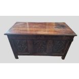 An 18th Century Oak Coffer, the hinged plank top above a carved frieze and three carved panels,