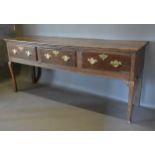 A George III oak dresser base with three drawers, brass handles and escutcheons raised upon cabriole