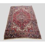 A North West Persian woollen carpet with a central medallion within an allover design upon a red,