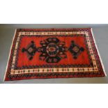 A North West Persian woollen rug with a central medallion upon a red and blue ground within multiple
