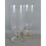 A pair of star cut glass storm vases with square pedestal bases, 40cms tall