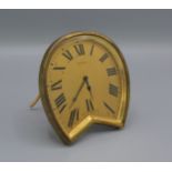 An Asprey Strut clock, the shaped brass case with gilded dial and Roman numerals, 10cms tall