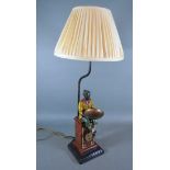 A painted metal table lamp in the form of a figure with a bowl upon a plinth with marble base, 30cms
