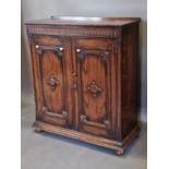 An oak side cabinet, the arcadian frieze above two panel doors raised upon low bun feet, 95cms wide,