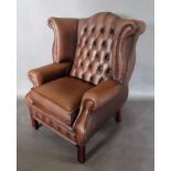 A button upholstered wingback armchair raised upon square legs