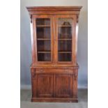 A Victorian walnut bookcase, the moulded cornice above two glazed doors, the lower section with a