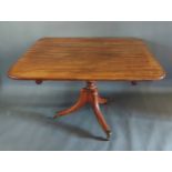 A Regency mahogany breakfast table raised upon a turned centre column with outswept legs, brass caps