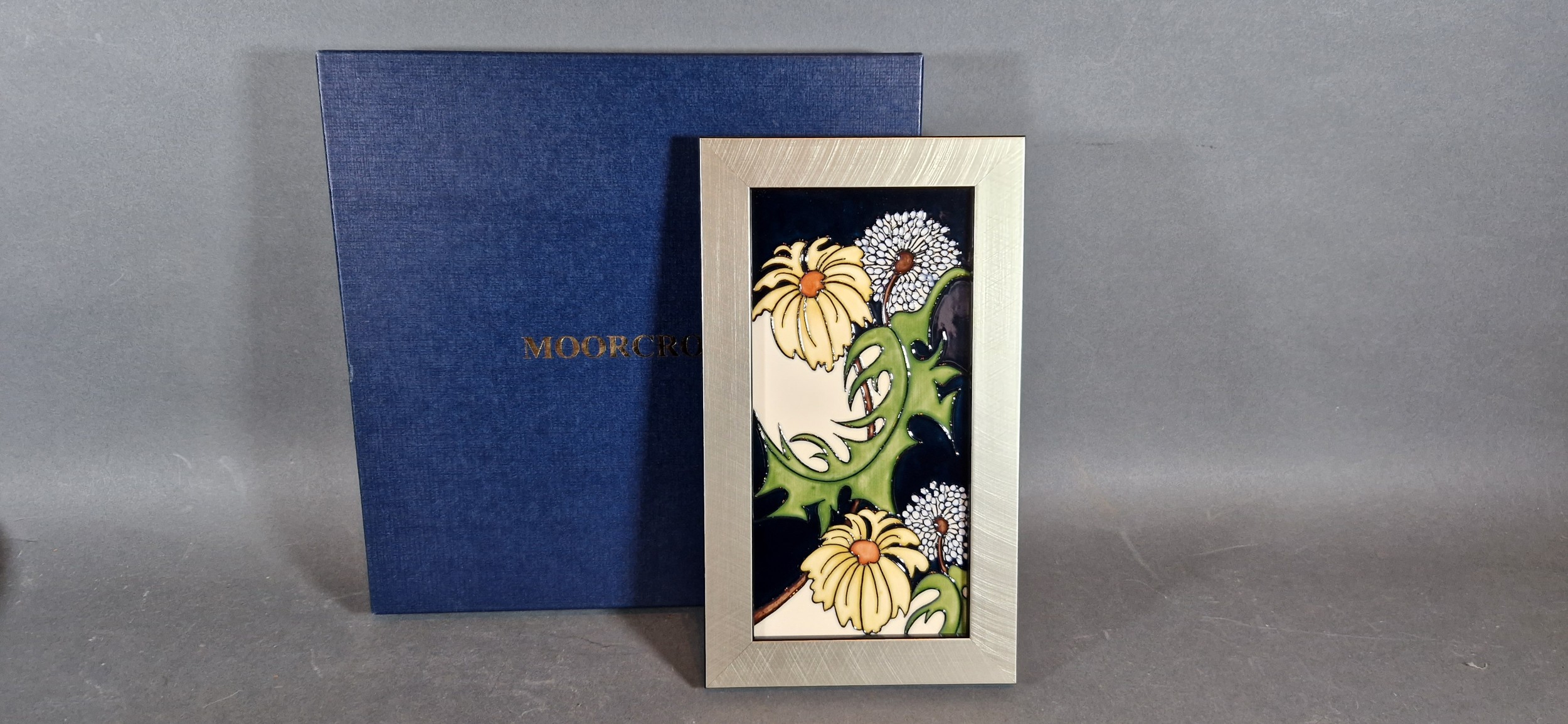 A Moorcroft tube lined rectangular plaque Daisy May pattern, 20.5cms x 10cms with original box