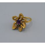 A yellow metal dress ring set with a single Amethyst within a flower head, 6.6 grams, ring size O