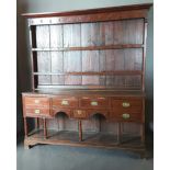 A George III oak Welsh dresser, the moulded cornice above a boarded shelf back, the lower section