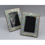 A pair of Sterling silver and enamel decorated photograph frames of rectangular form, 19.5cms X15cms