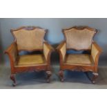 A pair of early 20th Century mahogany bergere arm chairs, each with a carved back above a cane