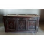 An 18th Century oak coffer, the hinged top above an arcadian frieze and three panel front flanked by