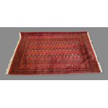 A Bokhara woollen rug with three rows of guls upon a red, cream and dark blue ground within