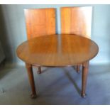 An Edwardian Mahogany Wind Out Extending Dining Table of circular form, the reeded top above a plain