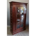 A 20th Century bookcase, with a moulded cornice above an astragal glazed door flanked by side