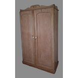 A pine wardrobe, the moulded cornice above two panel doors enclosing hanging space and drawers