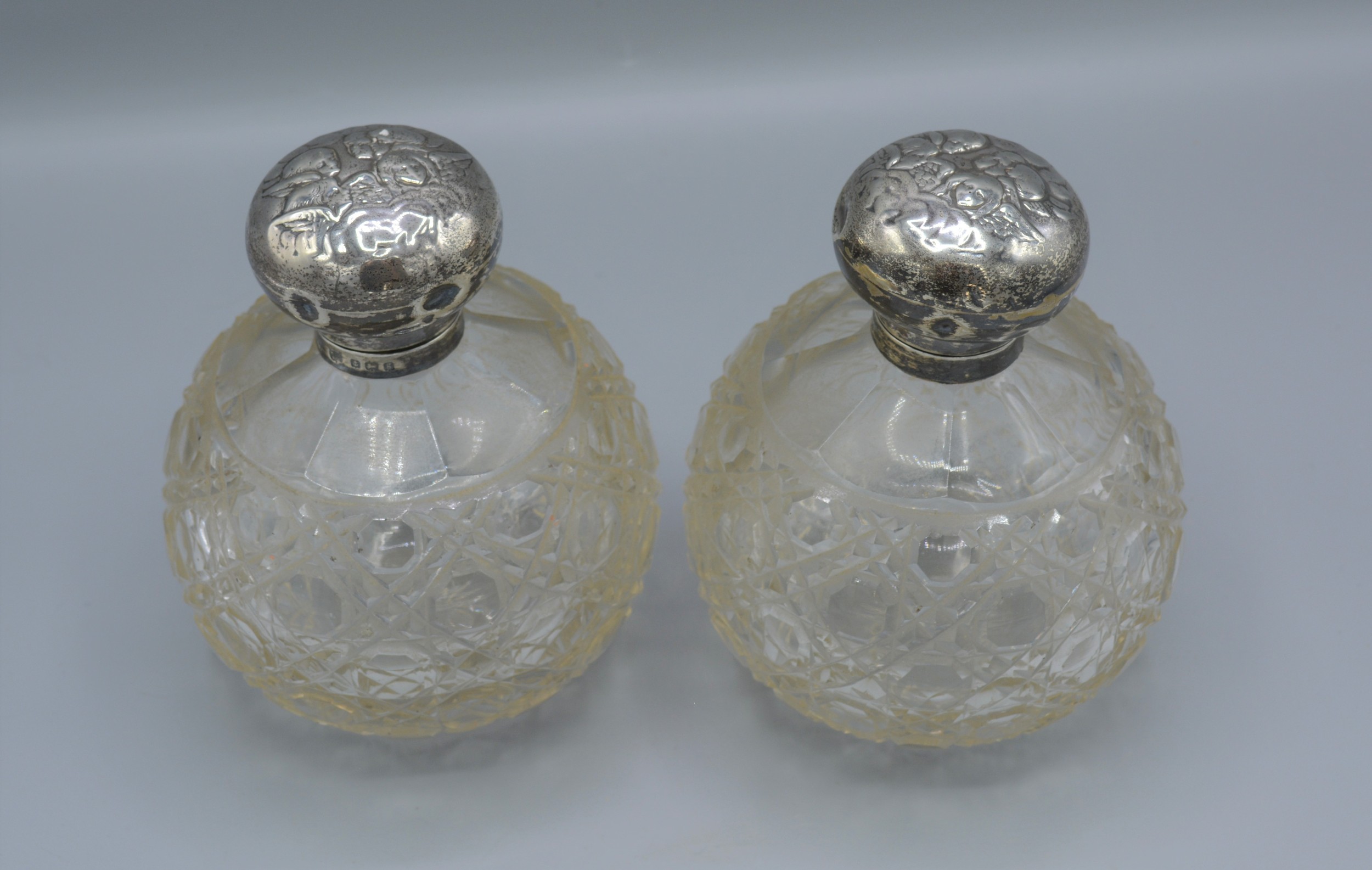 A pair of Edwardian silver and cut glass large scent bottles, decorated with whispers, Birmingham