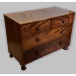 A mahogany chest of drawers with two short and two long drawers with knob handles raised upon bun