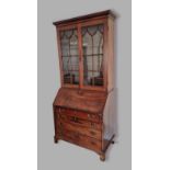 A George III mahogany bureau bookcase, the moulded cornice above two arched glazed doors enclosing