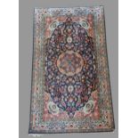 A Kashmir silk rug with a central medallion within an all over upon a red, blue and cream ground