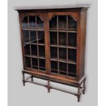 An early 20th Century oak display cabinet, the moulded top above two glazed doors enclosing