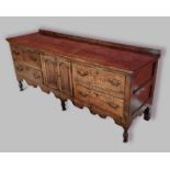 A George III oak dresser base with a moulded top above four central drawers flanked by cupboards and