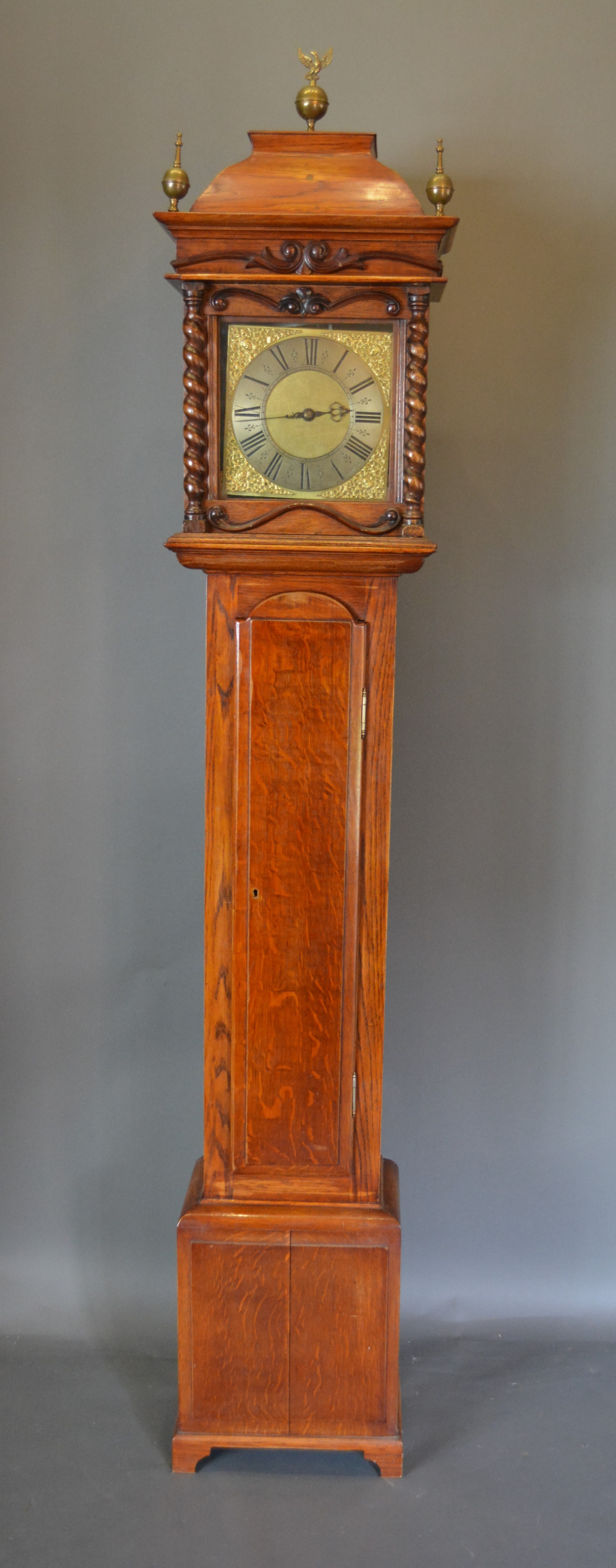 A 19th Century oak long case clock the rectangular hood with brass finials above a rectangular door,