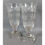 A pair of cut glass storm vases with square stepped bases, 29cms tall