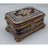 A late 19th Century French porcelain and enamel casket, the hinged cover enclosing a padded