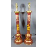 A pair of toleware table lamps each with Chinoiserie decoration on a red ground, 60cms tall