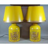 A pair of Toleware table lamps each decorated with an Armorial crest upon a mustard ground with