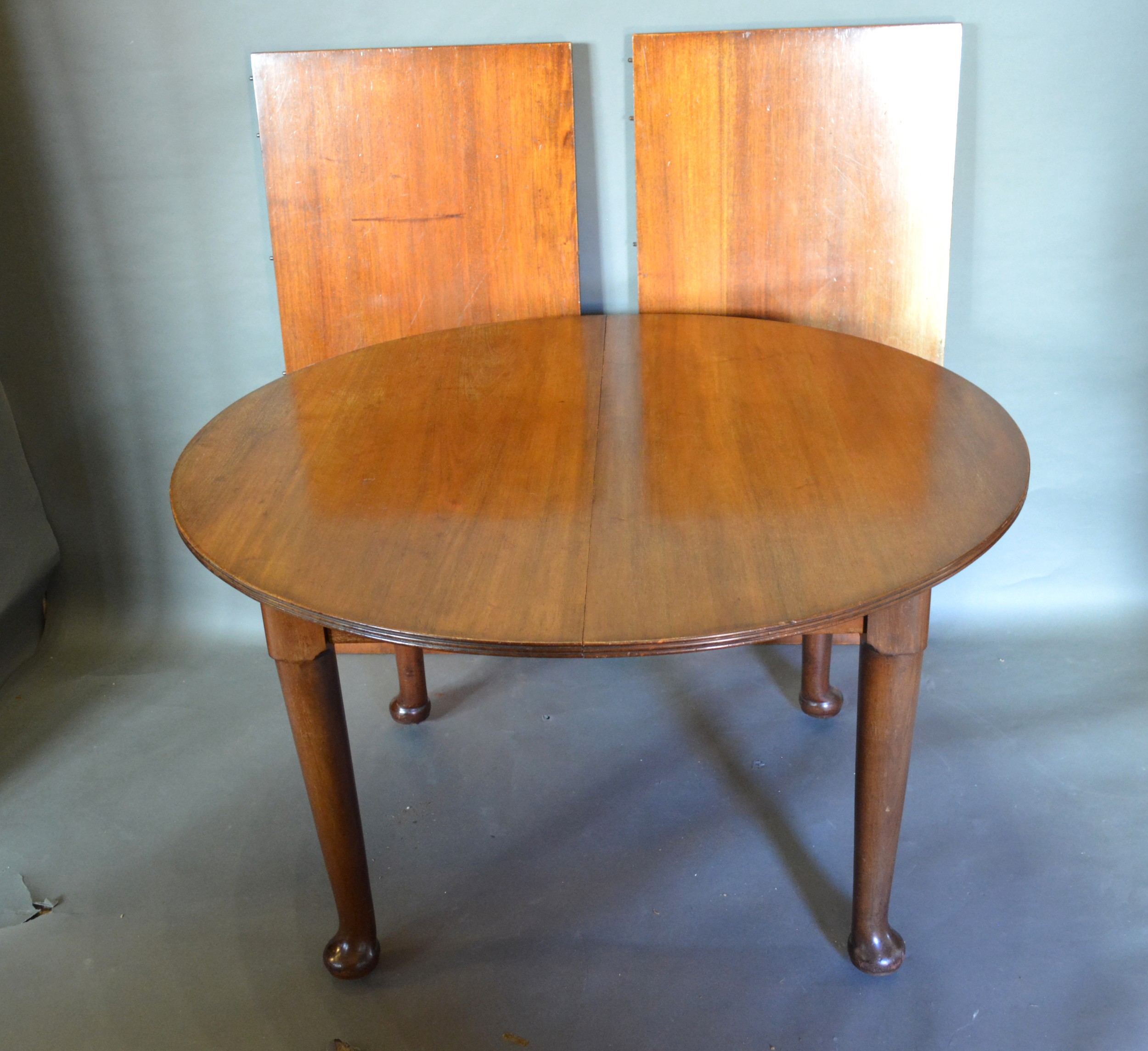 An Edwardian Mahogany Wind Out Extending Dining Table of circular form, the reeded top above a plain