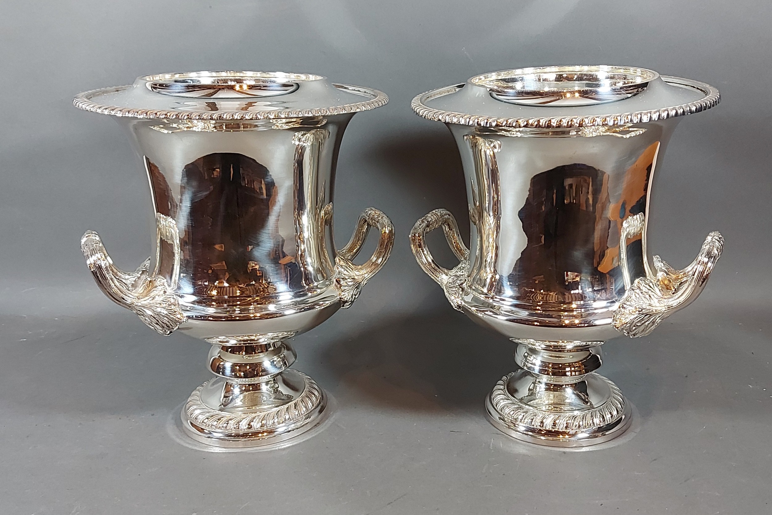 A pair of silver plated wine coolers, each with side handles upon pedestal bases, 28cms tall