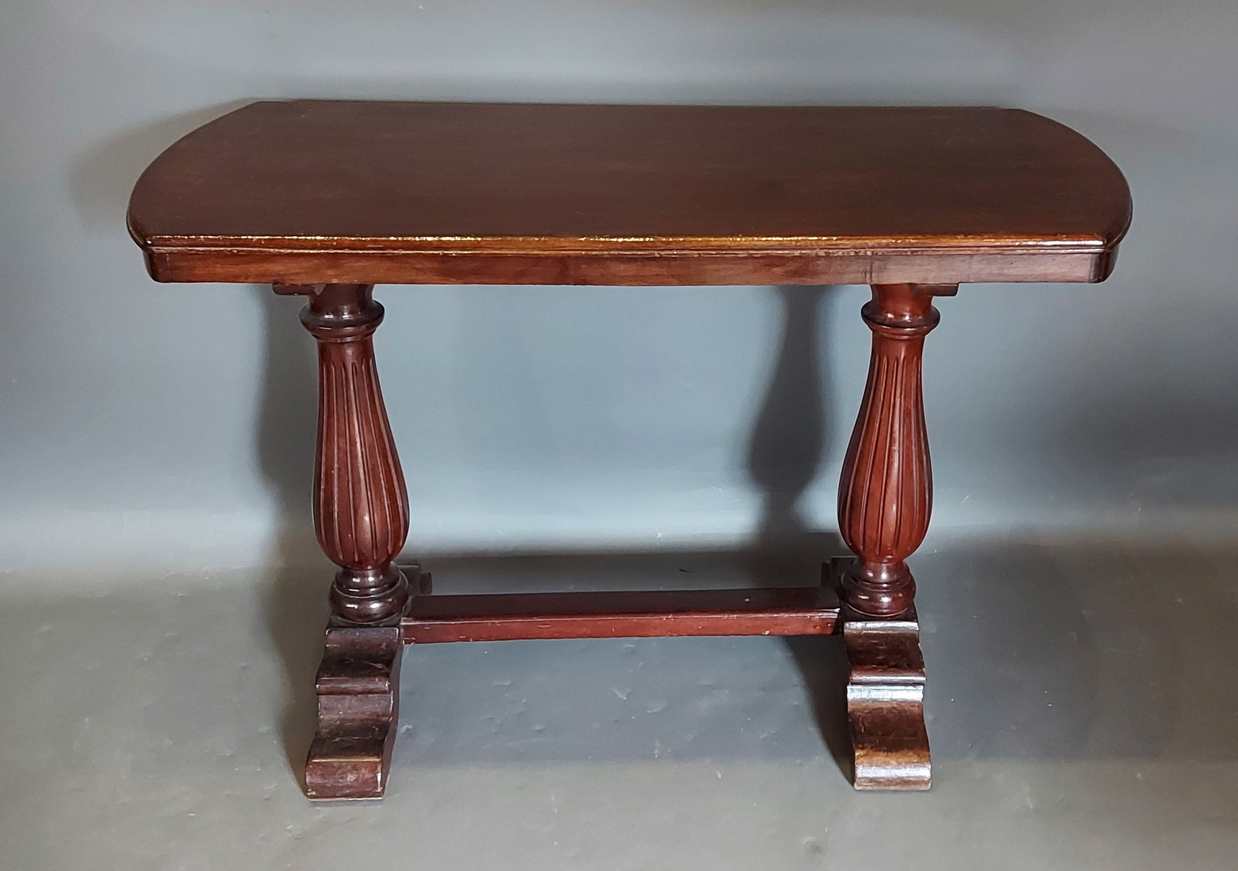 A 20th Century side table, with a shaped top above twin end reeded supports with stretcher, 114cms