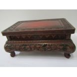 EASTERN CARVING, a red lacquered carved rectangular display stand, 19cm width