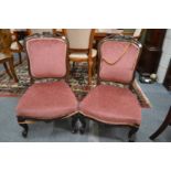 A pair of Victorian carved rosewood framed upholstered low chairs.