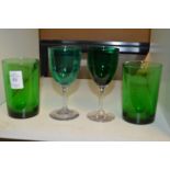 A pair of green glass tumblers and a pair of green glass wine glasses.