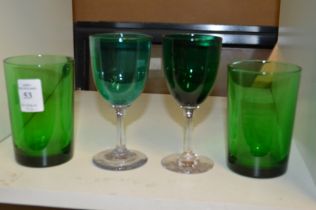 A pair of green glass tumblers and a pair of green glass wine glasses.