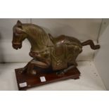 A Chinese cast bronze model of a horse on a hardwood stand.